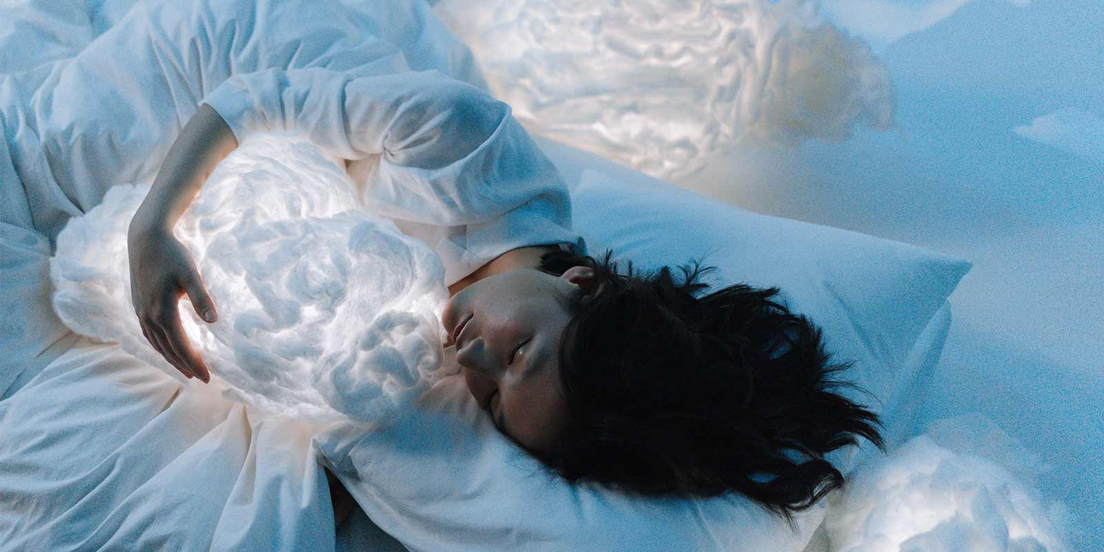 a woman sleeping holding a cloud-like pillow