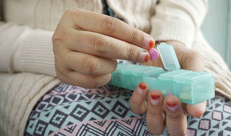 woman taking supplements out of the pill box to boost fertility